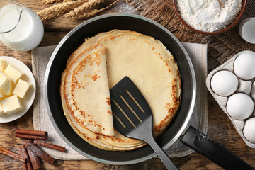 Pan with delicious pancakes on wooden table