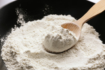 Taking wheat flour from bowl, closeup