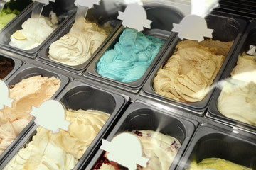 Showcase of different ice cream in metal tubs, closeup