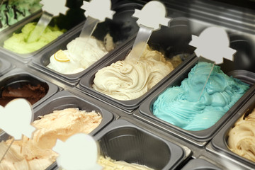 Showcase of different ice cream in metal tubs, closeup