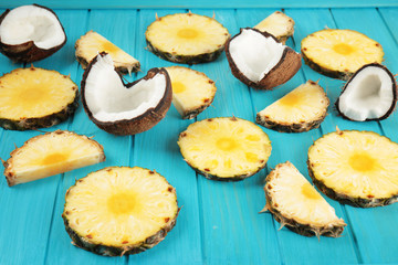 Composition of fresh coconut and pineapple slices on color wooden background