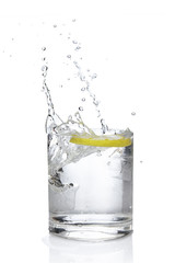 Ice cube and lemon splashing cocktail in oldfashioned glass. Drink with splashing citrus isolated on white.