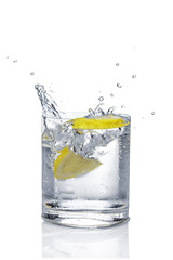Ice cube and lemon splashing cocktail in oldfashioned glass. Drink with splashing citrus isolated on white.