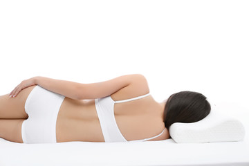 Young woman lying on bed with orthopedic pillow against white background. Healthy posture concept