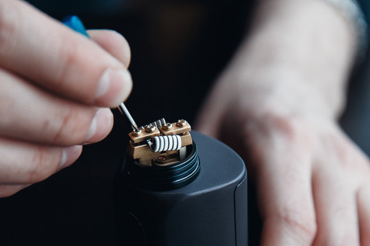 male master installs a coyle. Spiral for electronic evaporator and cigarette. Vape, vaping. Firing a coil.