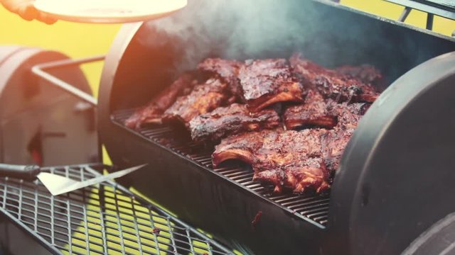 Cooking / smoking delicious juicy meat steaks and sausages on the grill on fire and Barbecue Smoker for smoke roasting