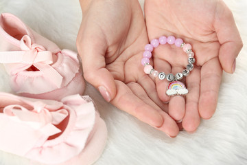 Bracelet with baby name Olivia in hands on white fluffy background