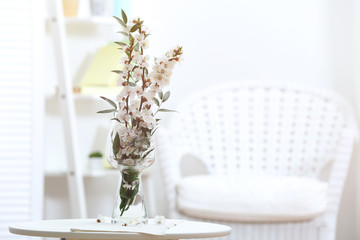 Vase with blossoming spring branches on table