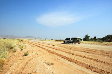 Geländewagen und Autos fahren auf sandiger Strasse in Namibia auf Safari