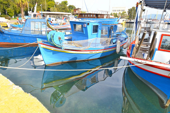blue boats reflected on sea at the industrial area of Eleusis Greece