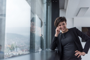 Elegant Woman Using Mobile Phone by window in office building