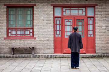 un homme chinois habillé en noir se tient debout de dos et se concentre pour débuter les exercices d'un art martial