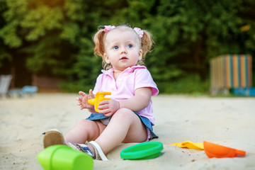 Kid girl playing in the sand. The concept of childhood and development.