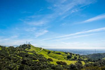 Green grass and blue sky on a mountainside with hiking trails and power tower.