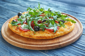 Tasty pizza with mushrooms, cherry tomatoes, olives and arugula on blue wooden background