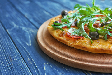 Tasty pizza with mushrooms, cherry tomatoes, olives and arugula on blue wooden background