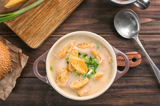 Delicious beer cheese soup with croutons and onions on table