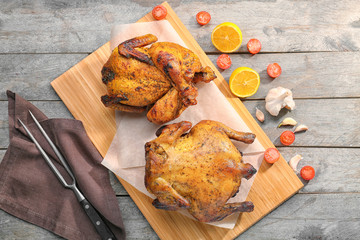 Board with roasted beer can chickens on wooden background