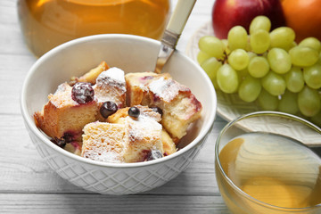 Delicious bread pudding with fruits and tea on wooden table
