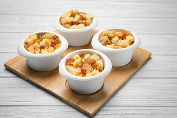 Baking bowls with bread pudding on wooden board