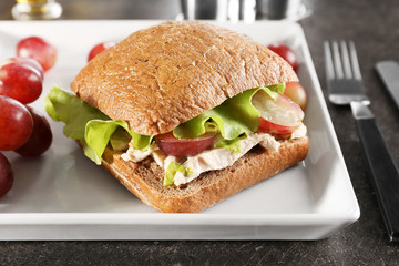 Plate with chicken salad in burger bun on table