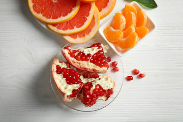 Plates with different citrus fruits on white wooden background