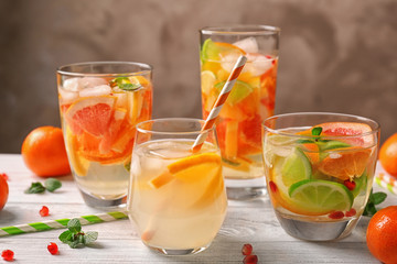 Glassware with refreshing citrus fruits cocktail on table