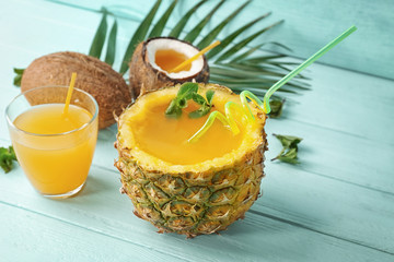 Cocktail in pineapple on wooden table