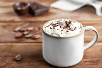 Cup of cocoa with whipped cream on wooden table
