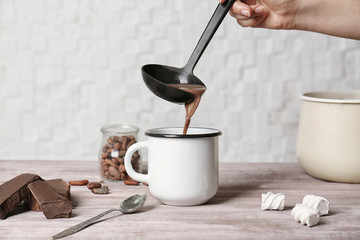 Pouring hot cocoa drink into cup on kitchen table
