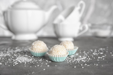 Tasty candies in coconut flakes on table