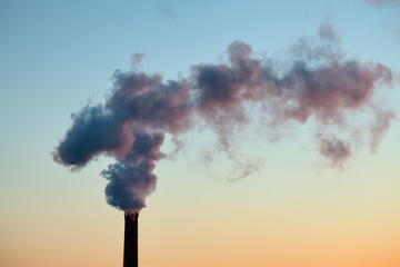 Smoke from the brick chimney of the plant in the early morning. The smoke from the pipe...