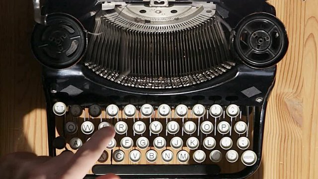 A person types on a old black vintage manual typewriter