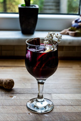 Sangria Cocktail in wine glass with lemon, cinnamon, fruits and ice.