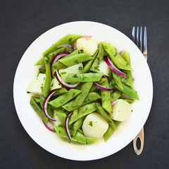 Green bean, potato and red onion salad with parsley, photographed overhead on slate with natural light