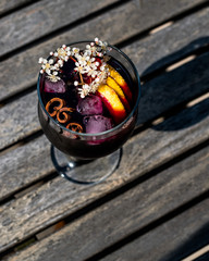 Sangria Cocktail in wine glass with lemon, cinnamon, fruits and ice.