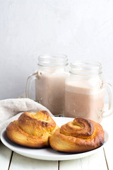 Buns and cocoa in mugs on a white background.
