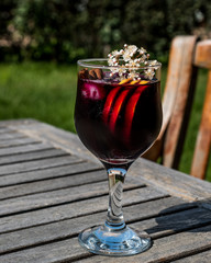 Sangria Cocktail in wine glass with lemon, cinnamon, fruits and ice.