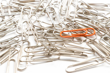 Red paper clip show different from the others on white background