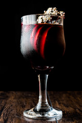 Sangria Cocktail in wine glass with lemon, cinnamon, fruits and ice.