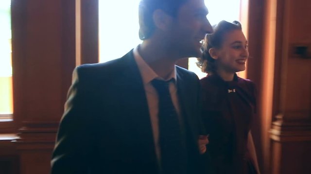 A man and a girl in retro style talk to each other. They walk arm-in-arm up the ladder
