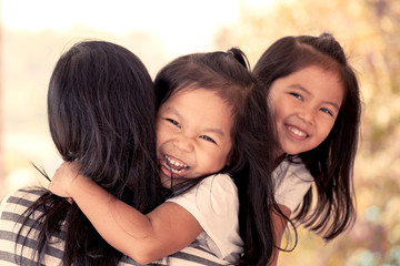 happy asian little girls hugging mother and having fun to play with mother in vintage color tone