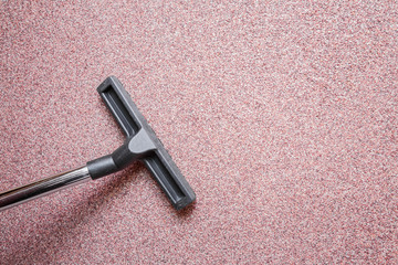 Professionally vacuum cleaner nozzle releasing decorative granite chipping plaster wall from dust. Early spring cleaning or regular clean up. Maid cleans house.
