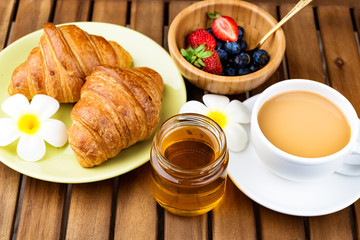 Cup of coffee and croissants on wooden background.