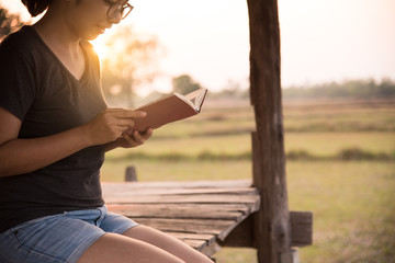 Asian girl reading a book on countryside background.