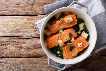 Salmon fillet baked with spinach, rosemary and roquefort cheese close-up. horizontal top view