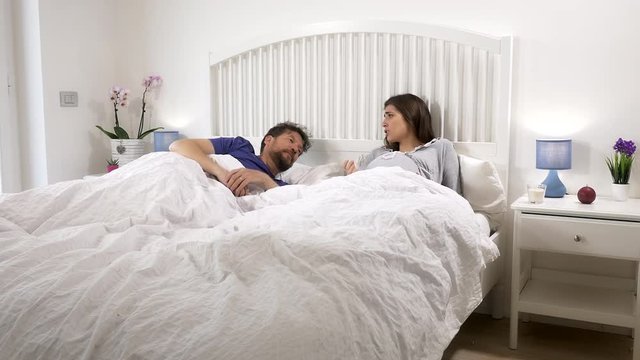 Pregnant woman with contractions in bed worried husband talking to her