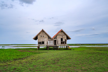 Damaged Old Two Red Roof Huts on The Green Field with the Blue Sky at Thalesap Songkhla and Thale Noi Waterfowl Reserve Park in Phatthalung ,Thailand

