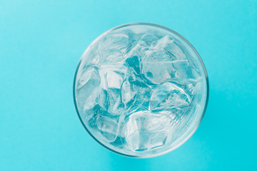 glass of soda with ice blocks isolated on blue background, top view