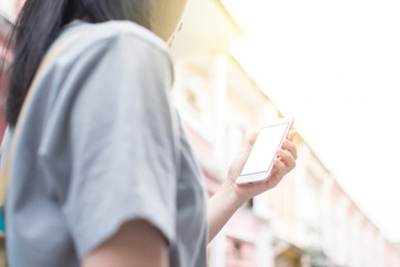 Young Asian traveling blogger or backpacker using route application on the mobile phone  to find the needed address in a city phuket, Thailand.